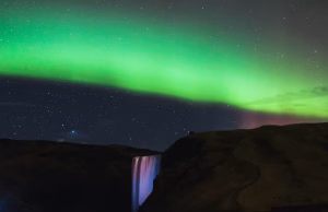 Aurora Borealis over a waterfall and autumn fields in Iceland