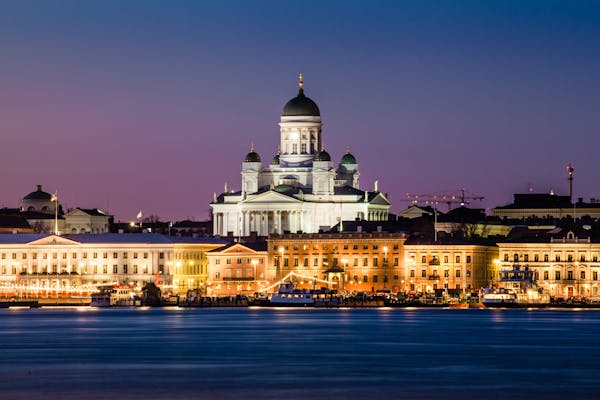 Helsinki Cathedral and waterfront at night, illuminated buildings against a deep purple-blue sky.