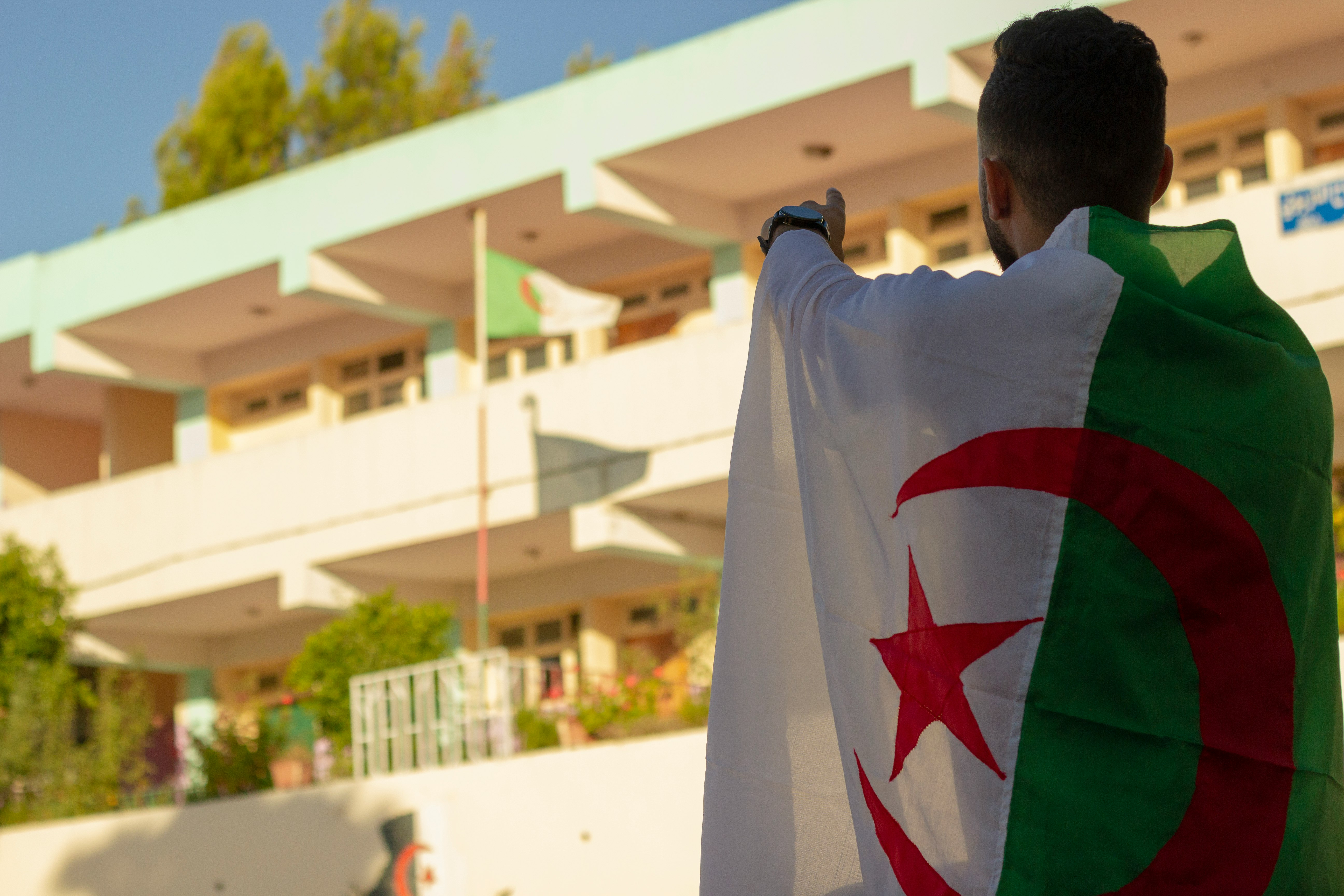 Man pointing toward the Algerian national flag with pride