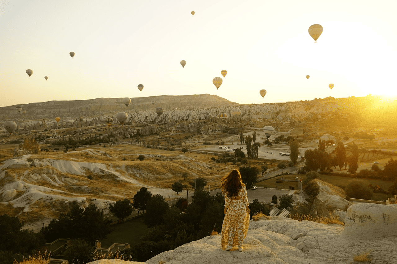 Woman enjoying hot air balloons floating over a valley
