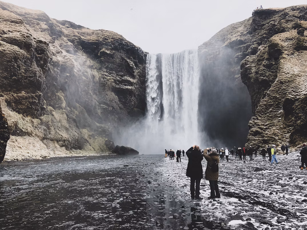 Tourists in layered clothing exploring Iceland’s waterfalls 
